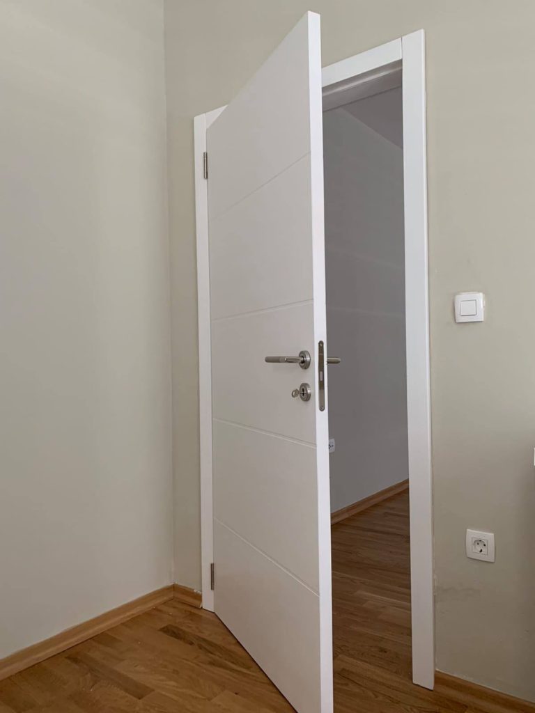 Bijela sobna vrata sa srebrenom štekom.